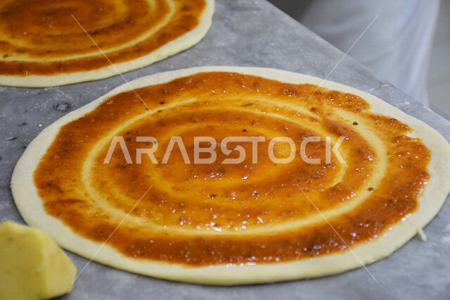 صورة مقربة لعجينة البيتزا مع معجون الطماطم (الصلصة) ، البيتزا والفطائر الشهية، تحضير فطيرة البيتزا، اكلات عربية شرقية، وجبات الطعام الشهية، المطاعم العربية، وجبات صحية