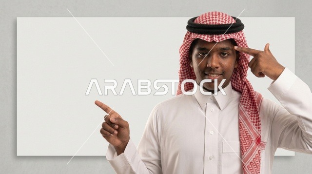 رجل سعودي يشير إلى لوحة بيضاء فارغة في الاستوديو