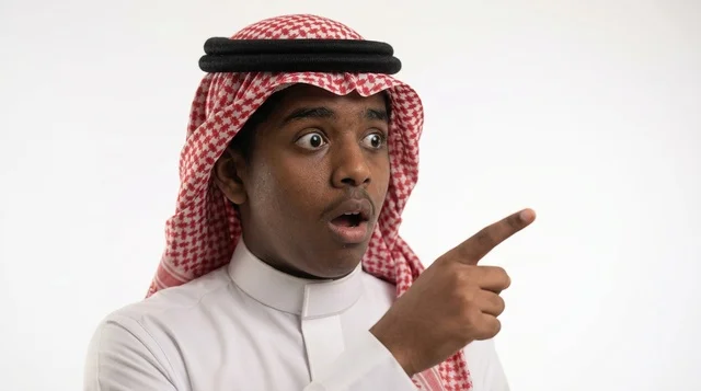 رجل سعودي متفاجئ يشير بإصبعه أمام خلفية بيضاء استوديو