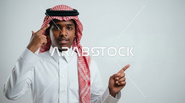 شاب سعودي بالزي التقليدي يشير إلى رأسه والجانب