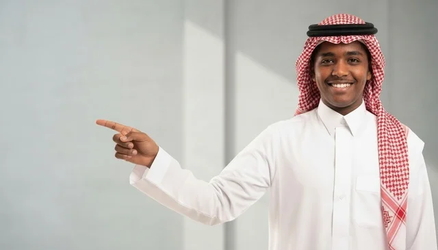 Saudi Man in Traditional Thobe Pointing to Copy Space