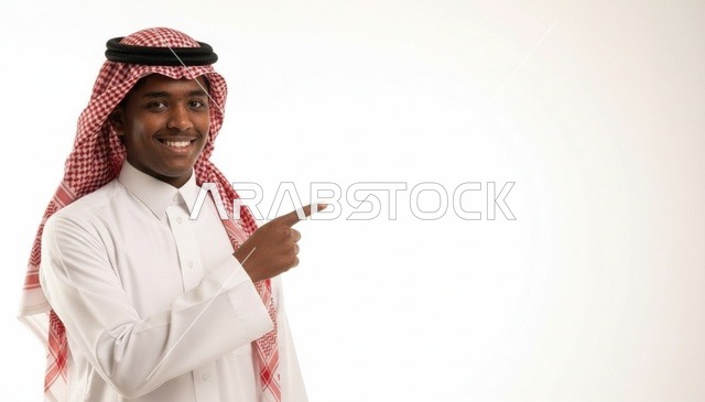 رجل سعودي يرتدي الشماغ يشير إلى مساحة إعلانية بيضاء