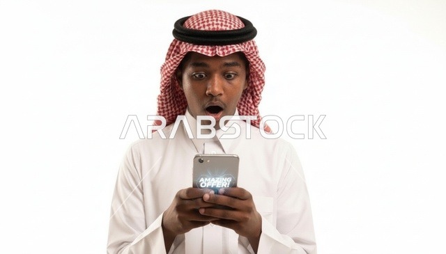 رجل سعودي مصدوم ينظر إلى الهاتف الذكي في الاستوديو