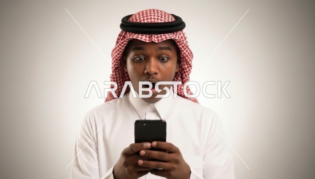شاب سعودي مصدوم ينظر إلى الهاتف الذكي في الاستوديو
