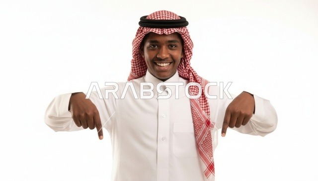 شاب سعودي مبتسم يشير بإصبعيه إلى الأسفل خلفية بيضاء