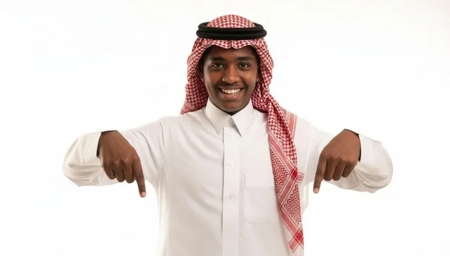 شاب سعودي مبتسم يشير بإصبعيه إلى الأسفل خلفية بيضاء