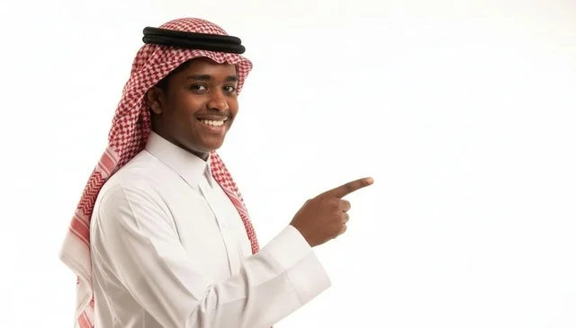 شاب سعودي مبتسم يشير بإصبعه على خلفية بيضاء نظيفة