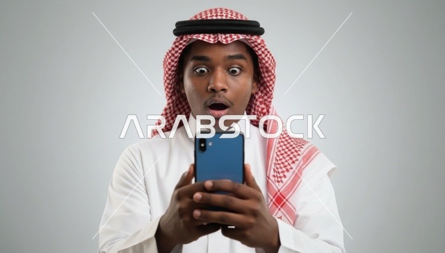 رجل سعودي مصدوم ينظر إلى هاتفه الذكي في الاستوديو