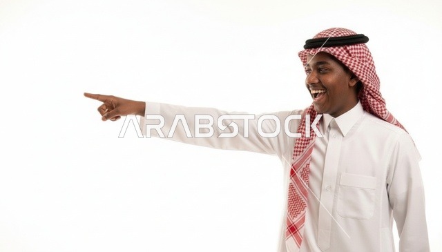 شاب سعودي مبتسم يشير بإصبعه على خلفية بيضاء