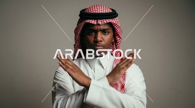 رجل سعودي يشير بالرفض بيدين متقاطعتين في الاستوديو