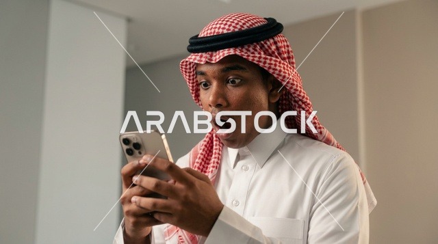 Surprised Saudi Arab Man Looking at Smartphone Indoors