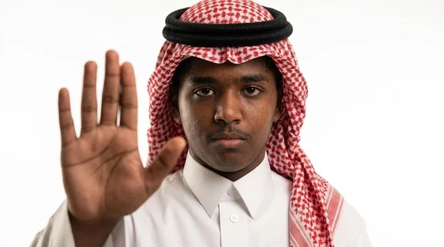 رجل سعودي بالشماغ التقليدي يشير بيده للتوقف