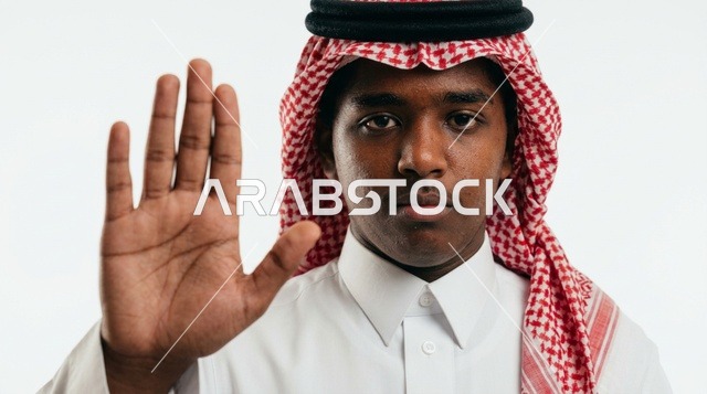 شاب سعودي يرتدي الشماغ يشير بيده بعلامة التوقف