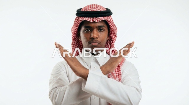 شاب سعودي يشير بعلامة الرفض أمام خلفية بيضاء