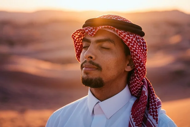 رجل سعودي بالشماغ التقليدي في الصحراء وقت الغروب