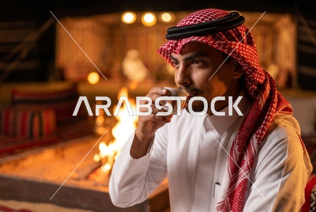 رجل سعودي يشرب القهوة العربية بجانب شبة النار ليلاً بالمخيم