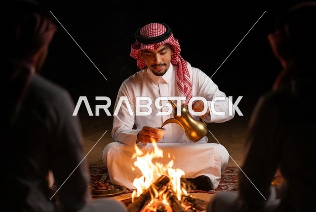 رجل سعودي يسكب القهوة العربية بجانب شبة النار ليلا