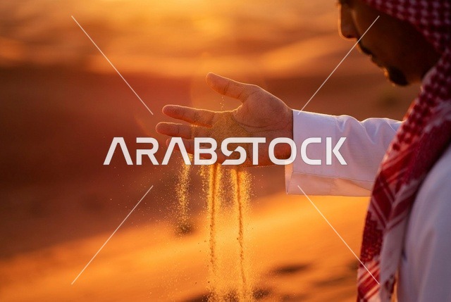 رجل سعودي يسكب الرمل في الصحراء وقت الغروب
