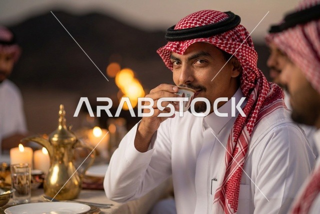 رجل سعودي يشرب القهوة العربية على مائدة عشاء صحراوية