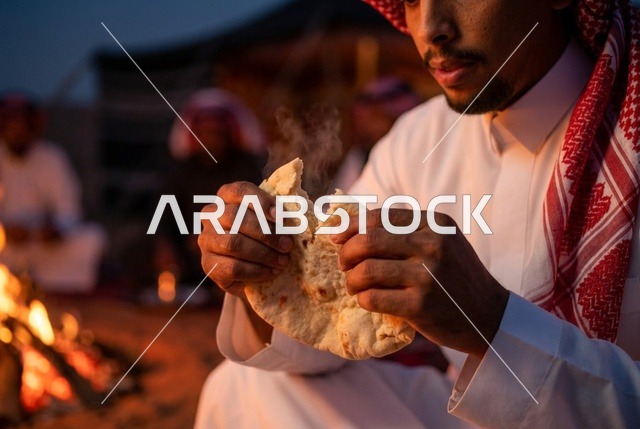 رجل سعودي يقطع الخبز الساخن بجانب شبة النار ليلاً