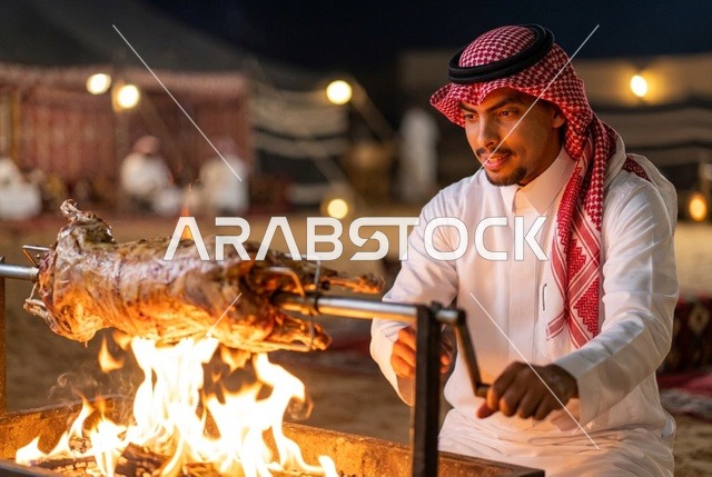 رجل سعودي يشوي خروفاً كاملاً على النار في مخيم صحراوي