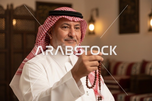 رجل سعودي بالزي التقليدي يمسك مسبحة في مجلس تراثي