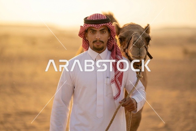 رجل سعودي مع جمل في الصحراء وقت الغروب