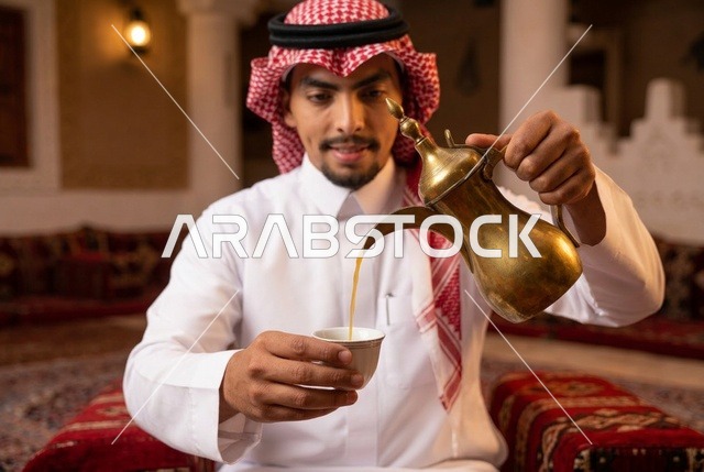 رجل سعودي يصب القهوة العربية من دلة ذهبية في المجلس