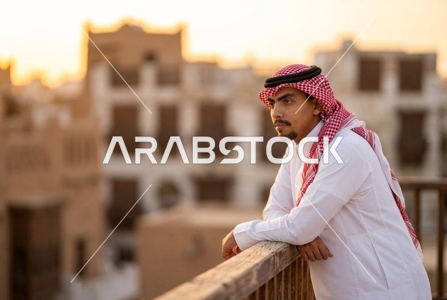 رجل سعودي على شرفة في بلدة تاريخية وقت الغروب