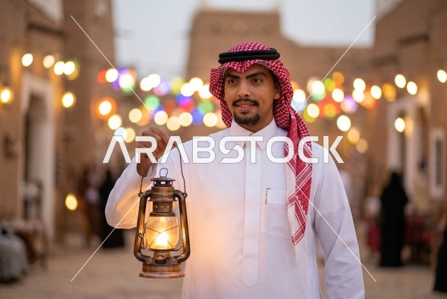 رجل سعودي يرتدي الزي التقليدي ويحمل فانوس رمضان