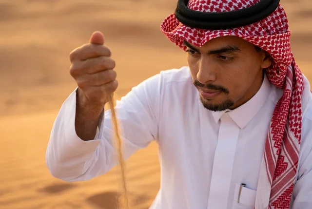 رجل سعودي بالزي التقليدي والشماغ وقت الغروب بالصحراء