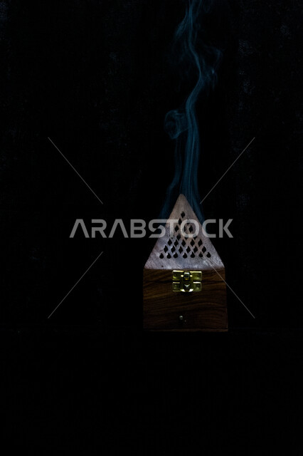 صورة إبداعية لمبخرة خشبية، التعطر والتطيب، بخور عربية، بخور خليجية سعودية، المسك والعود، خلفية سوداء