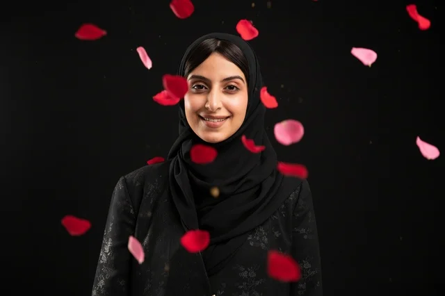 امرأة عربية بالحجاب والعباءة مع تساقط بتلات الورد الأحمر