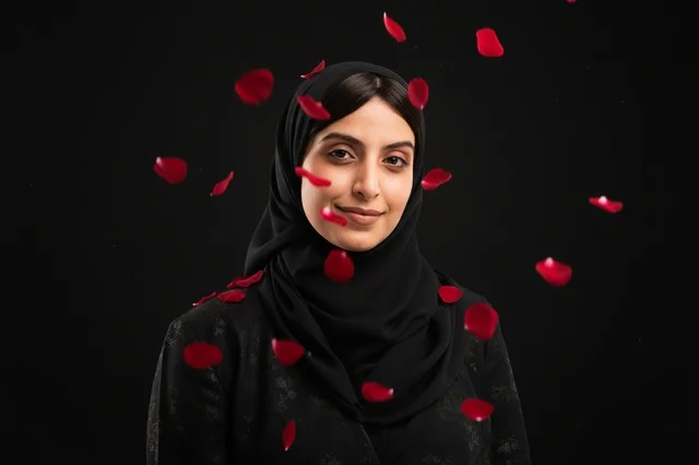 امرأة عربية بالحجاب الأسود مع بتلات الورد الأحمر المتساقطة