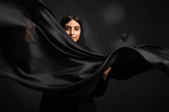 امرأة عربية بالحجاب الأسود مع قماش متطاير في الاستوديو