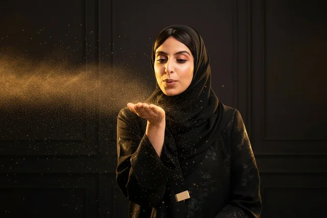 امرأة عربية بالعباءة تنفخ غباراً ذهبياً في الاستوديو امرأة عربية بالعباءة تنفخ غباراً ذهبياً في الاستوديو
