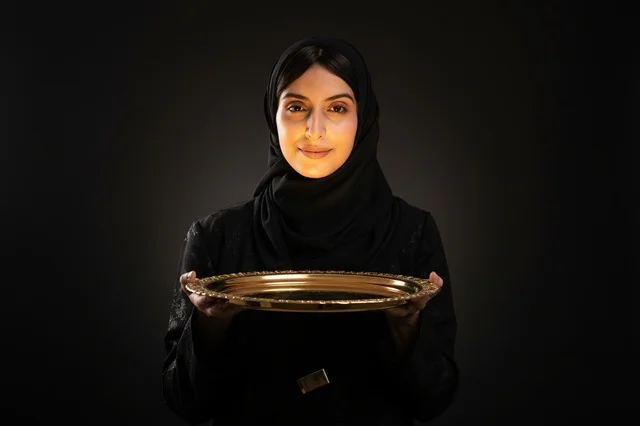 Saudi Woman Holding Golden Tray on Dark Background