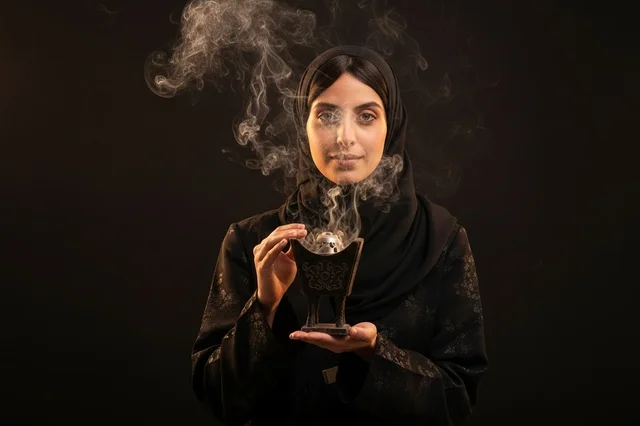 امرأة عربية ترتدي العباءة وتحمل مبخرة البخور التقليدية