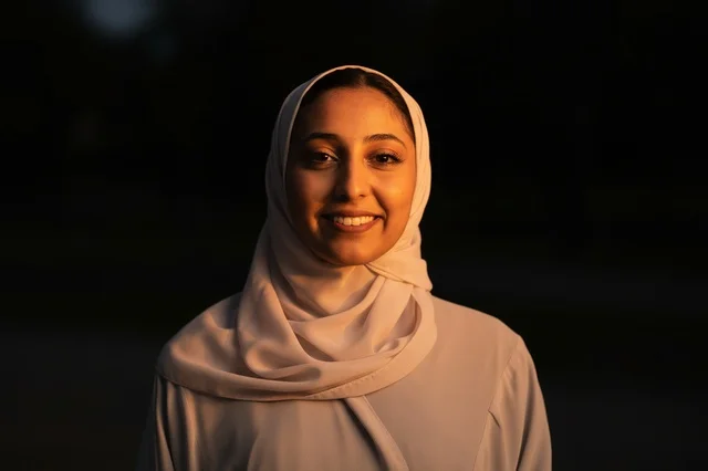 امرأة عربية مبتسمة ترتدي حجاب متطاير على خلفية سوداء
