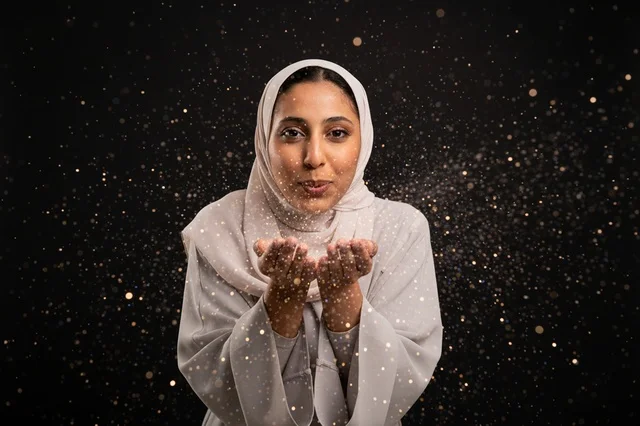 Arab Woman Blowing Gold Glitter on Dark Background
