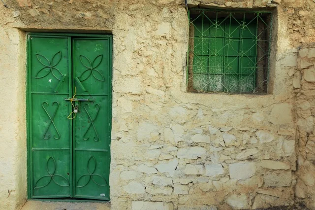 Traditional Green Door and Rustic Stone Wall in Oman