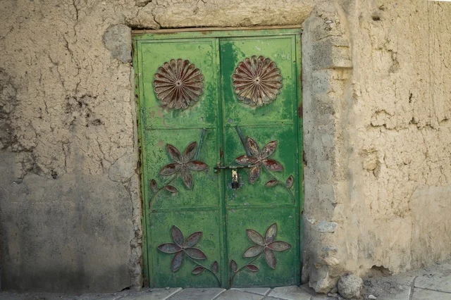 Historic Green Metal Door in Traditional Omani Wall