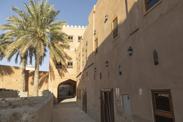 مباني طينية عربية تقليدية مع شجرة نخيل في ممر تراثي