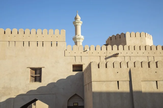 جدران قلعة نزوى الطينية التاريخية ومئذنة المسجد في عمان