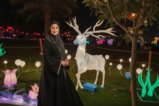 امرأة عربية بالعباءة تقف في مهرجان الأضواء ليلاً