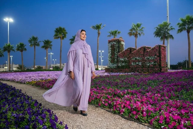 امرأة عربية بعباءة بنفسجية تمشي في حديقة زهور ليلا امرأة عربية بعباءة بنفسجية تمشي في حديقة زهور ليلا