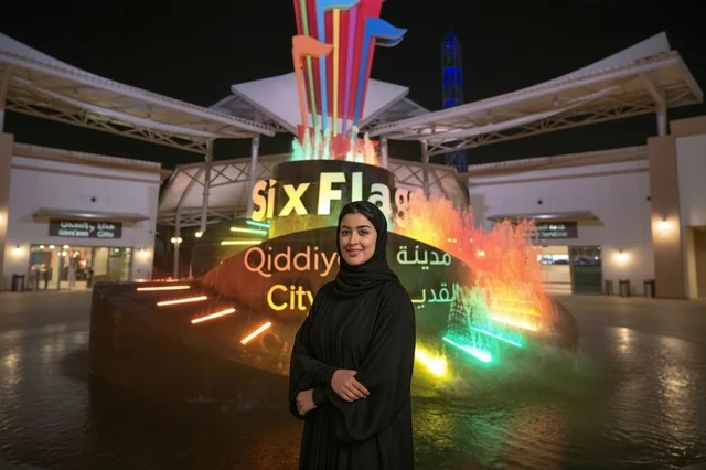 امرأة سعودية أمام نافورة القدية المضيئة في الرياض ليلاً