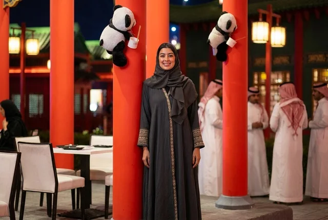 امرأة سعودية بالعباءة في فعاليات موسم الرياض ليلاً