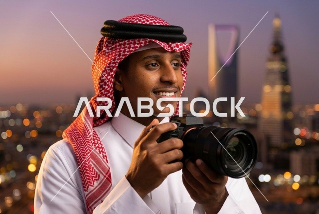 مصور سعودي يمسك كاميرا أمام أفق الرياض بالمساء