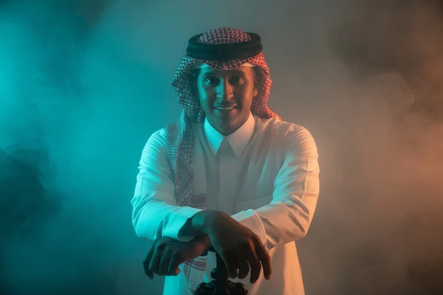 رجل سعودي بالزي التقليدي والشماغ مع خلفية ضبابية ملونة